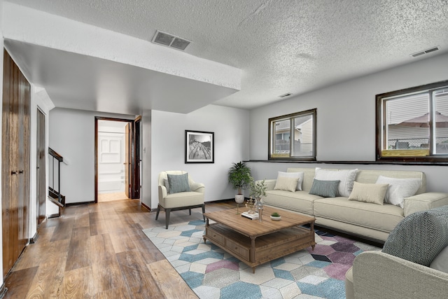 living room featuring a healthy amount of sunlight, a textured ceiling, and light wood-type flooring