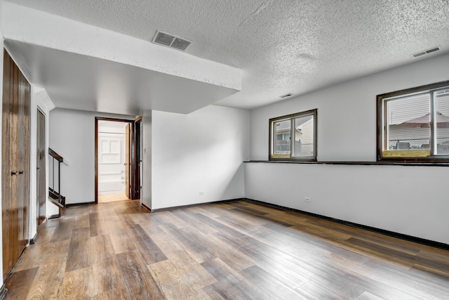 unfurnished room featuring a healthy amount of sunlight, wood-type flooring, and a textured ceiling