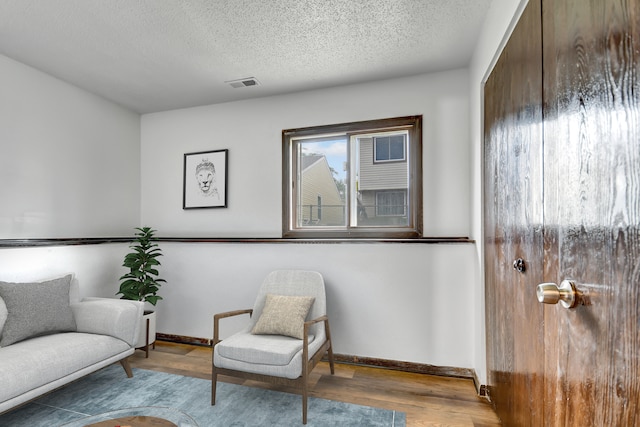 living area featuring a textured ceiling and wood-type flooring