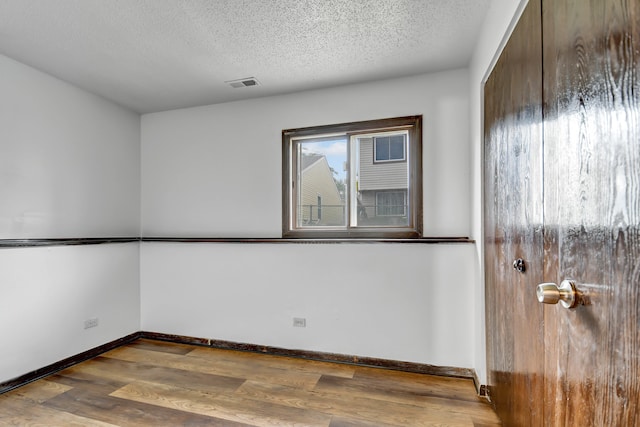 spare room with a textured ceiling and dark hardwood / wood-style floors