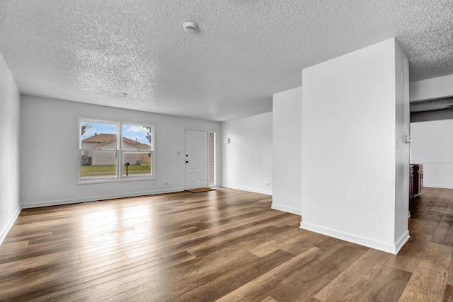 unfurnished living room with dark wood-type flooring and a textured ceiling