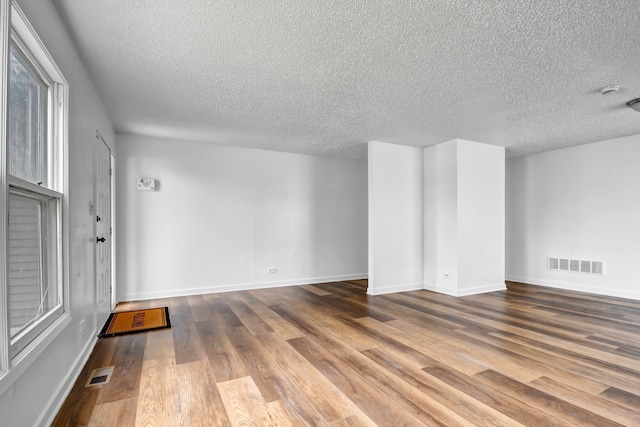 empty room with wood-type flooring and a textured ceiling