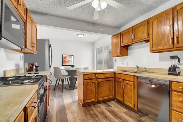 kitchen featuring hardwood / wood-style floors, ceiling fan, appliances with stainless steel finishes, a textured ceiling, and sink