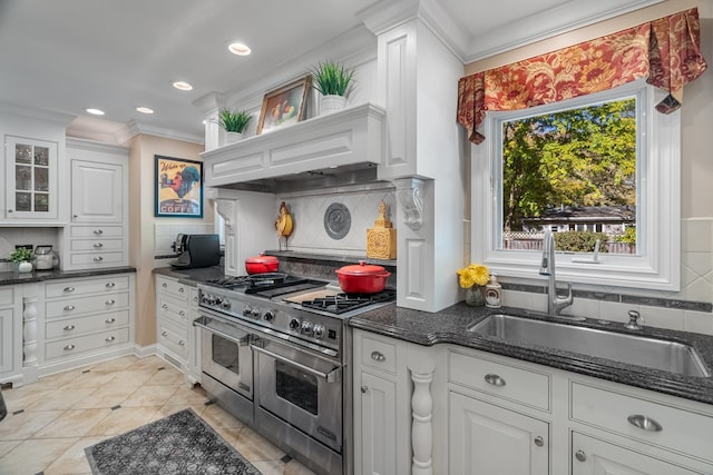 kitchen featuring range with two ovens, white cabinetry, and sink