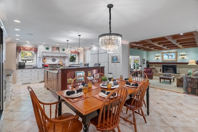 tiled dining area featuring crown molding, an inviting chandelier, beam ceiling, coffered ceiling, and a brick fireplace