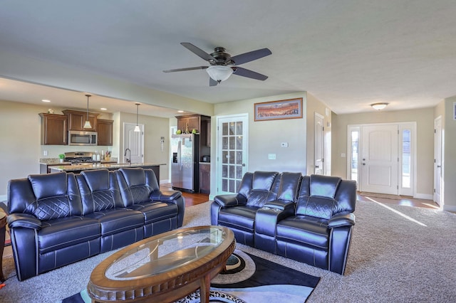 living room featuring carpet flooring, sink, and ceiling fan