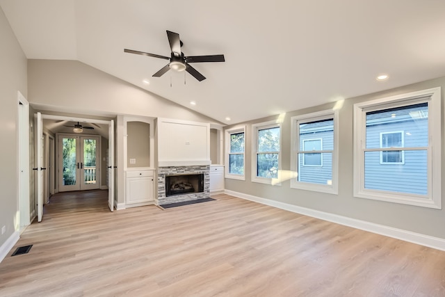 unfurnished living room featuring french doors, vaulted ceiling, light hardwood / wood-style flooring, and plenty of natural light