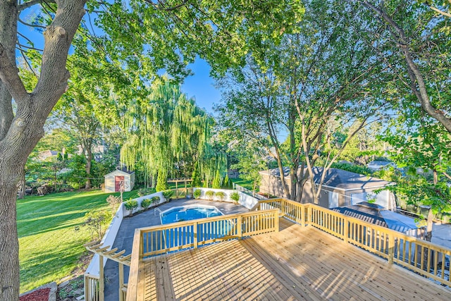 view of pool with a wooden deck, a storage shed, and a lawn