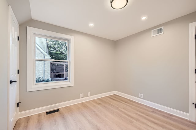 spare room with vaulted ceiling and light hardwood / wood-style floors