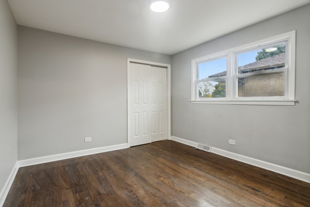 unfurnished bedroom featuring dark wood-type flooring and a closet