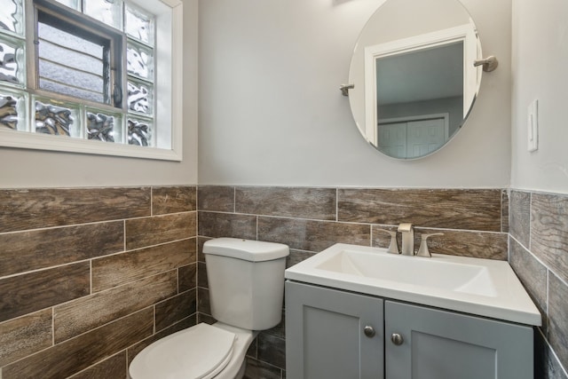 bathroom featuring toilet, vanity, and tile walls