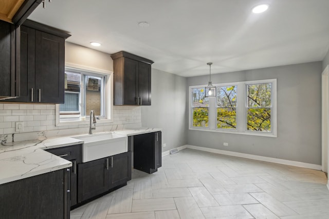 kitchen featuring pendant lighting, a wealth of natural light, sink, and backsplash