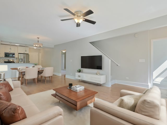 living room with light hardwood / wood-style floors and ceiling fan with notable chandelier