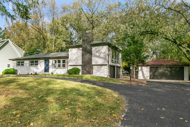 view of front of home with a front yard, a garage, and an outbuilding