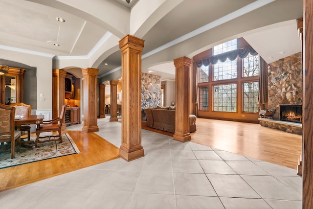 interior space with light hardwood / wood-style flooring, ornamental molding, a fireplace, and decorative columns