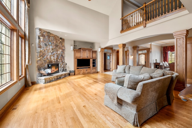 living room with ornate columns, hardwood / wood-style flooring, and a healthy amount of sunlight