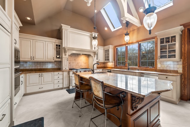 kitchen featuring decorative backsplash, an island with sink, and hanging light fixtures