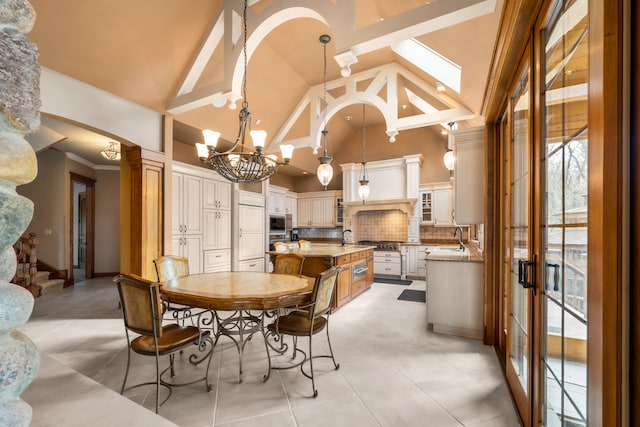 tiled dining room featuring beam ceiling, sink, high vaulted ceiling, and a skylight