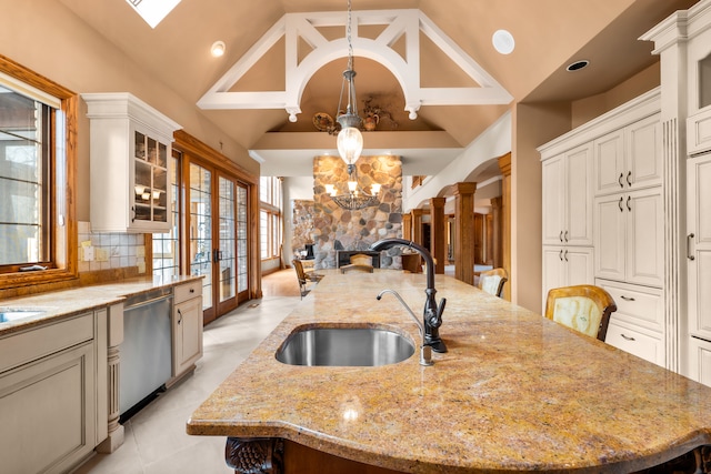 kitchen featuring a large island, vaulted ceiling, sink, and light stone counters