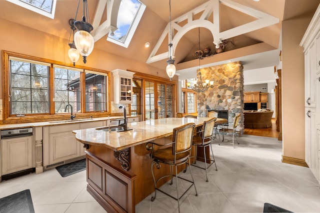 kitchen featuring light stone countertops, sink, an island with sink, pendant lighting, and high vaulted ceiling