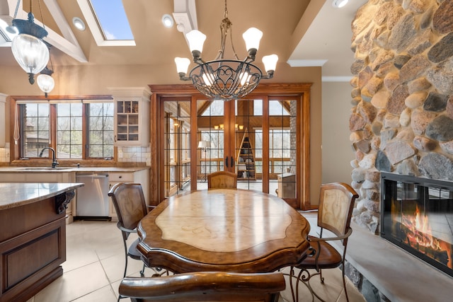 tiled dining area featuring a wealth of natural light, lofted ceiling with skylight, french doors, and a fireplace