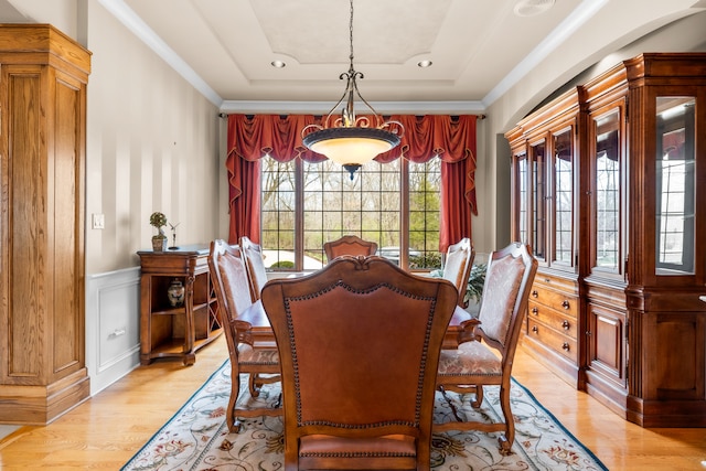 dining space with light hardwood / wood-style floors and a tray ceiling