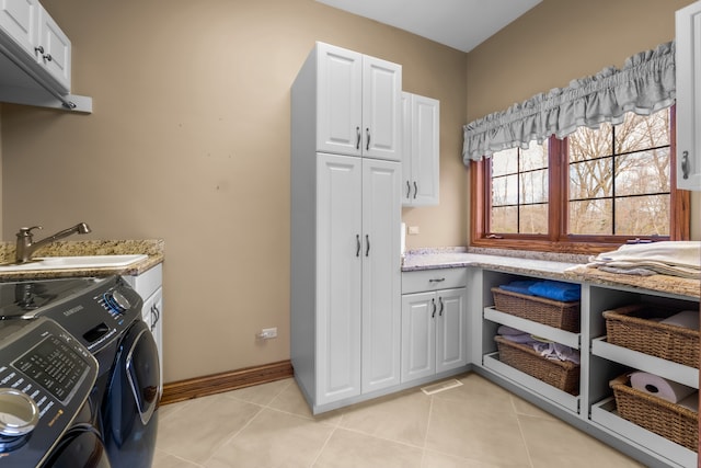 laundry area featuring light tile patterned floors, sink, separate washer and dryer, and cabinets