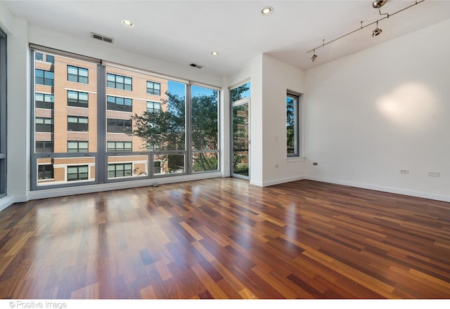 empty room with rail lighting and dark hardwood / wood-style flooring