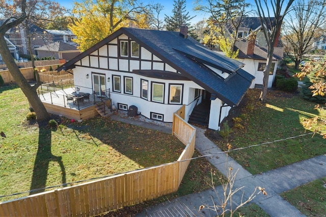 rear view of property with a chimney, stucco siding, a shingled roof, a lawn, and fence