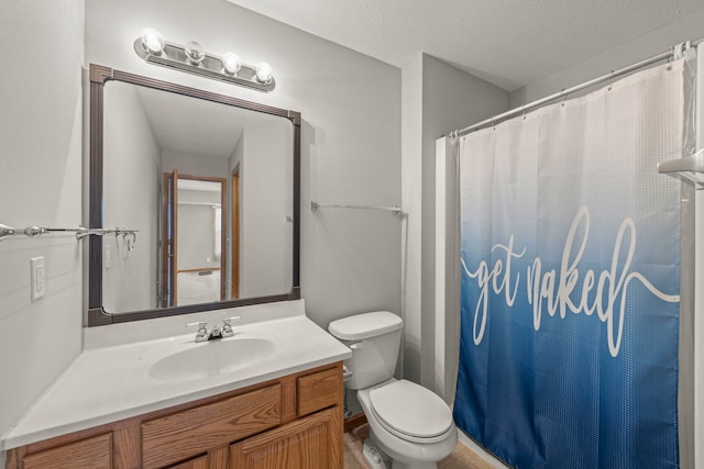 bathroom with vanity, curtained shower, toilet, and a textured ceiling