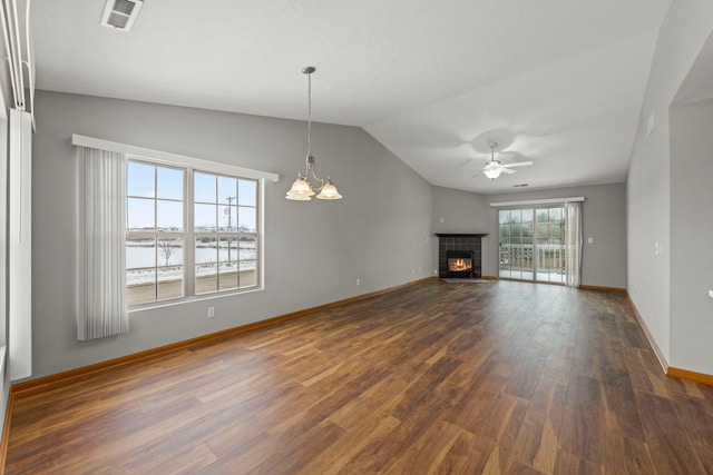 unfurnished living room with dark hardwood / wood-style flooring, vaulted ceiling, a fireplace, a water view, and ceiling fan with notable chandelier