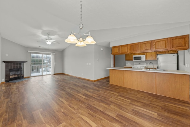 kitchen featuring white appliances, pendant lighting, wood-type flooring, a fireplace, and lofted ceiling