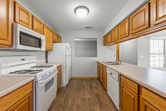 kitchen featuring a textured ceiling, white appliances, dark wood-type flooring, and sink