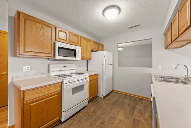 kitchen featuring a textured ceiling, dark hardwood / wood-style flooring, white appliances, and sink