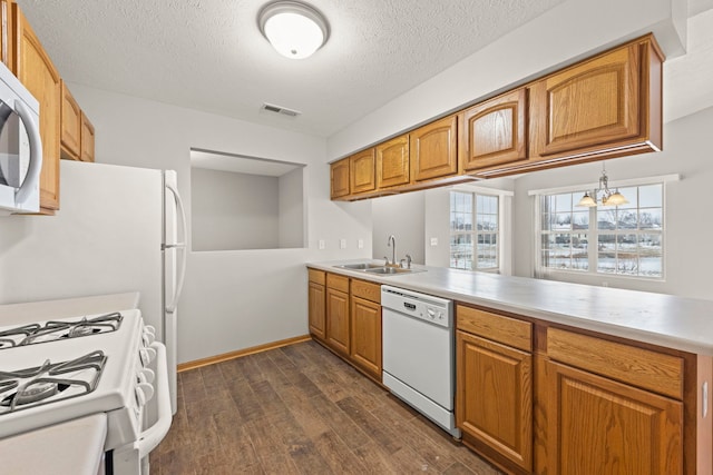 kitchen with white appliances, sink, dark hardwood / wood-style floors, kitchen peninsula, and a chandelier