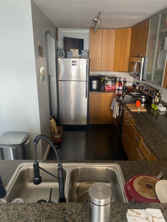 kitchen featuring dark stone countertops, stainless steel appliances, and sink