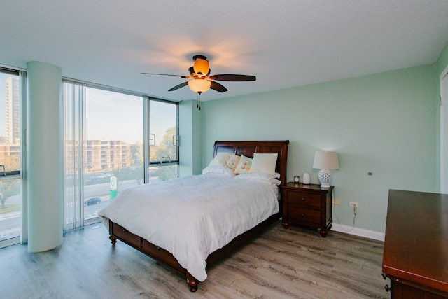 bedroom featuring floor to ceiling windows, access to exterior, ceiling fan, and wood-type flooring