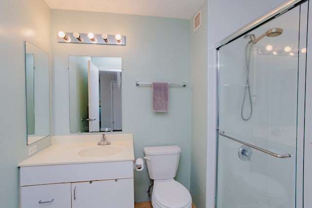 bathroom featuring vanity, an enclosed shower, and toilet