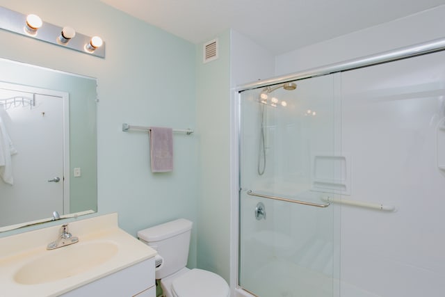 bathroom featuring vanity, toilet, and a shower with door