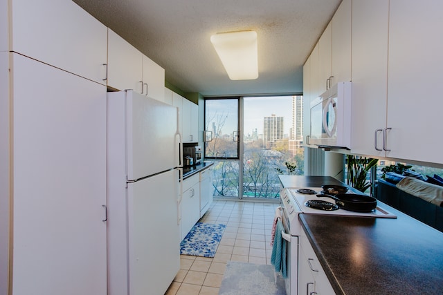 kitchen featuring white cabinetry, a wall of windows, white appliances, and a wealth of natural light