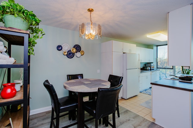 dining space featuring light hardwood / wood-style floors, a textured ceiling, and a notable chandelier