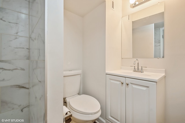 bathroom with vanity, tiled shower, and toilet