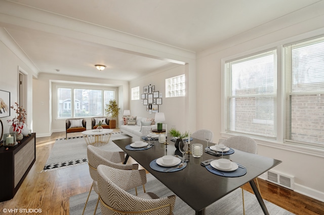 dining space featuring crown molding and light hardwood / wood-style floors