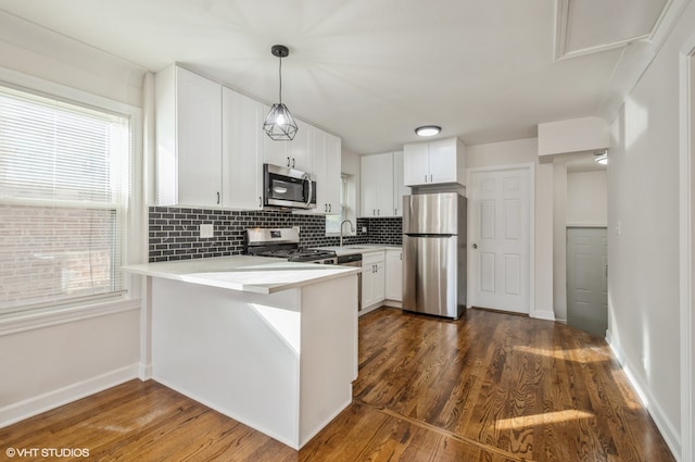 kitchen featuring white cabinets, kitchen peninsula, stainless steel appliances, and dark hardwood / wood-style floors