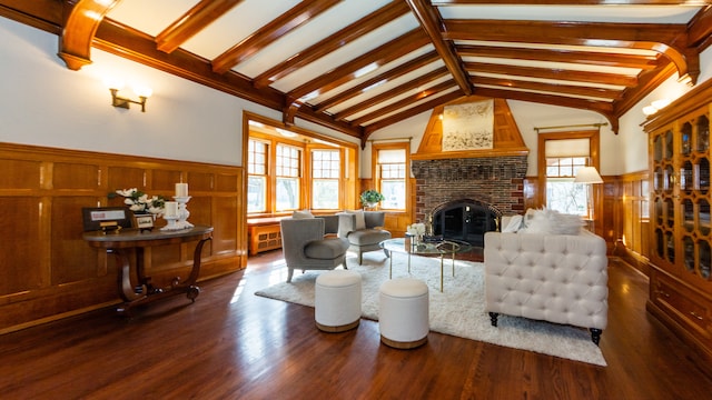 living room featuring lofted ceiling with beams, a healthy amount of sunlight, dark wood-type flooring, and a fireplace