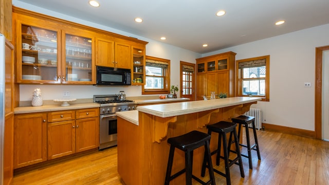 kitchen featuring a kitchen bar, high end range, light hardwood / wood-style flooring, radiator, and a kitchen island