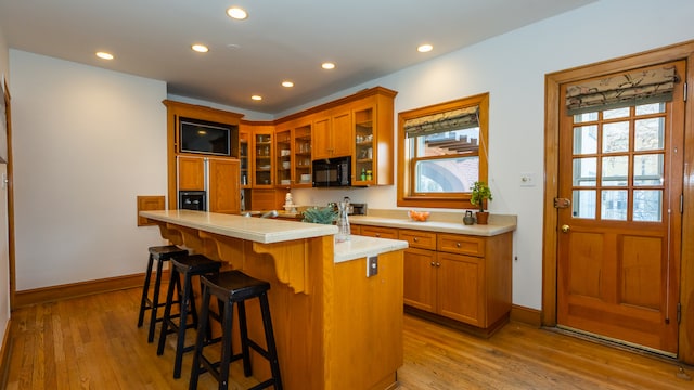 kitchen featuring a healthy amount of sunlight, a breakfast bar area, a kitchen island, and light wood-type flooring