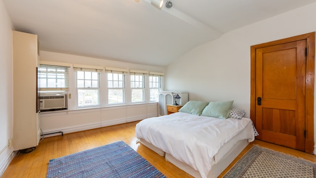 bedroom with cooling unit, lofted ceiling, and light hardwood / wood-style flooring