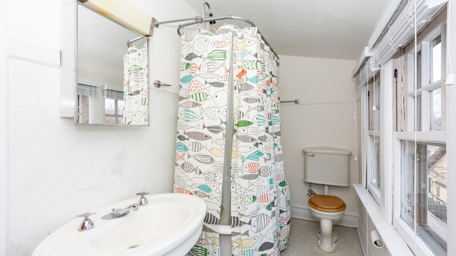 bathroom featuring toilet, tile patterned flooring, sink, and a wealth of natural light