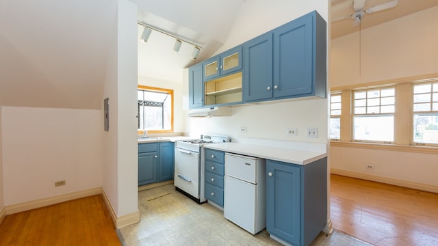 kitchen featuring lofted ceiling, blue cabinetry, track lighting, and white gas range oven